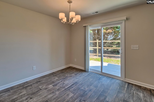 spare room featuring a chandelier and dark wood-type flooring