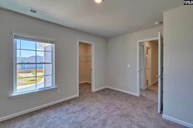 unfurnished bedroom featuring light colored carpet, a spacious closet, and a closet