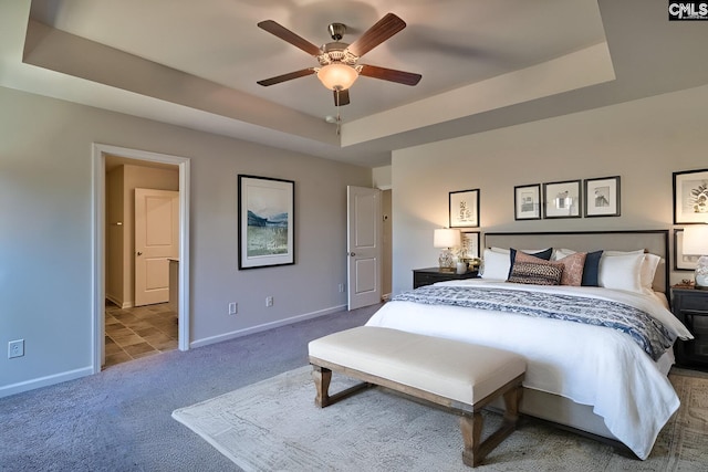 carpeted bedroom featuring a raised ceiling and ceiling fan