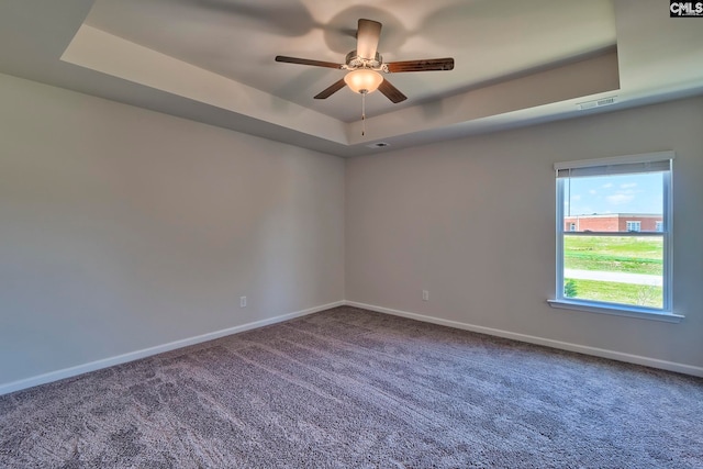 carpeted empty room with a tray ceiling and ceiling fan