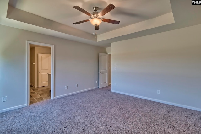 unfurnished room featuring light colored carpet, a raised ceiling, and ceiling fan