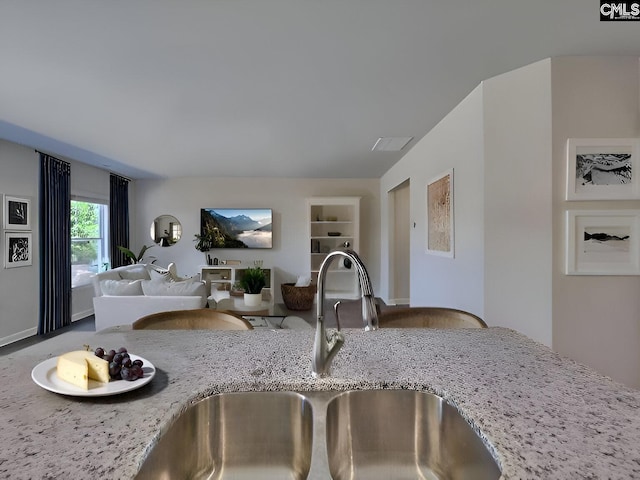 kitchen with light stone counters, sink, and built in features