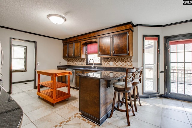 kitchen with tasteful backsplash, sink, light tile patterned flooring, and a healthy amount of sunlight