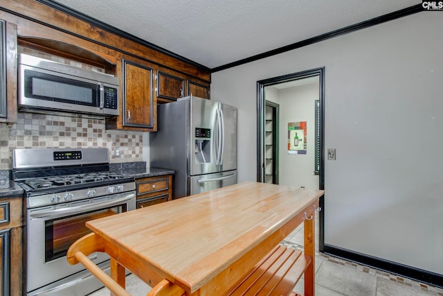 kitchen with crown molding, light tile patterned floors, a textured ceiling, appliances with stainless steel finishes, and tasteful backsplash