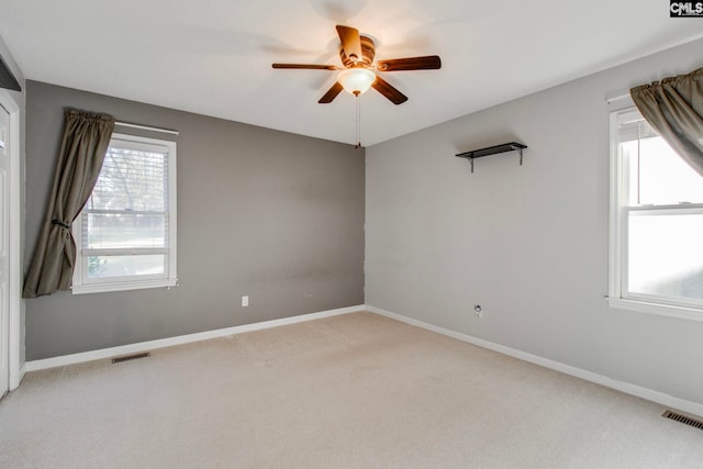 empty room featuring plenty of natural light, ceiling fan, and light carpet