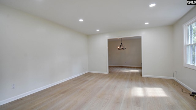 empty room featuring a chandelier and light hardwood / wood-style floors