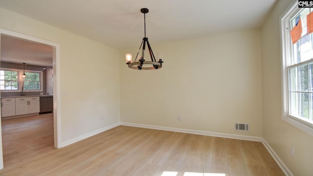 empty room with an inviting chandelier and light hardwood / wood-style flooring