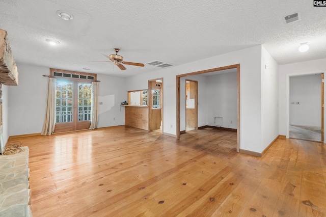 unfurnished living room with ceiling fan, light hardwood / wood-style floors, and a textured ceiling