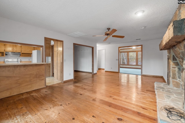 unfurnished living room with ceiling fan, a textured ceiling, and light hardwood / wood-style flooring