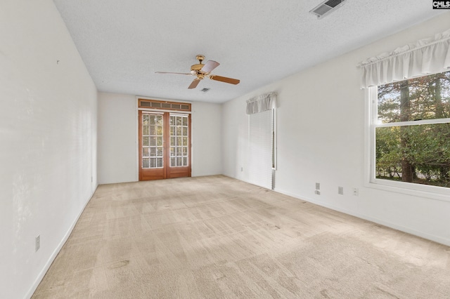 carpeted spare room featuring ceiling fan, french doors, and a textured ceiling