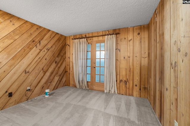 spare room featuring a textured ceiling and wooden walls