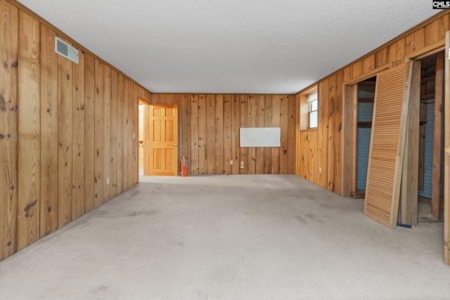 spare room featuring carpet, wood walls, and crown molding