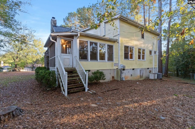 rear view of house featuring cooling unit and a sunroom