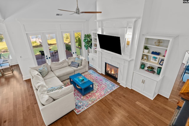 living room featuring hardwood / wood-style floors, high vaulted ceiling, french doors, and ceiling fan