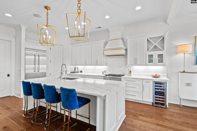 kitchen with white cabinets, sink, appliances with stainless steel finishes, custom range hood, and beverage cooler