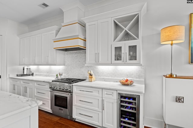 kitchen featuring tasteful backsplash, white cabinetry, high end range, and beverage cooler