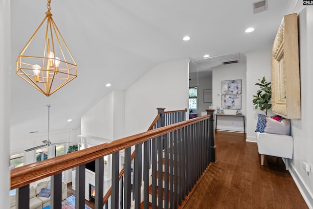 corridor with vaulted ceiling, dark hardwood / wood-style floors, and a notable chandelier