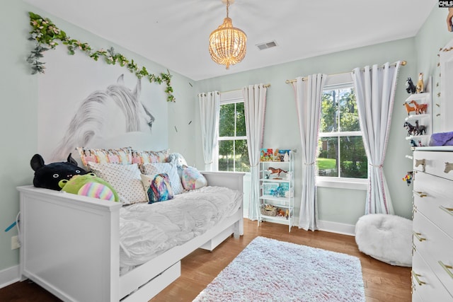 bedroom with hardwood / wood-style floors and a notable chandelier