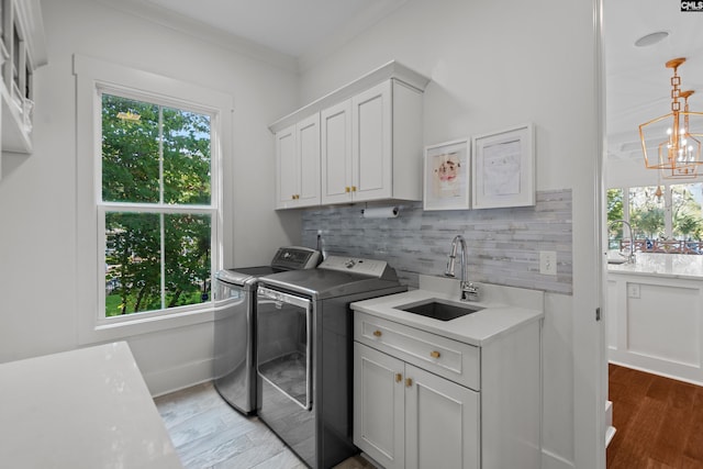 washroom featuring cabinets, sink, hardwood / wood-style flooring, washing machine and clothes dryer, and a chandelier