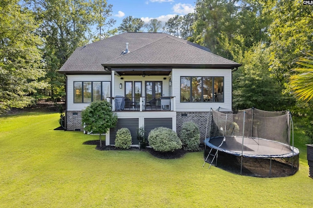 back of house featuring a lawn and a trampoline