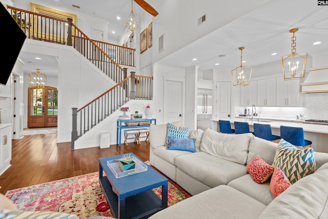 living room with sink, a towering ceiling, and dark wood-type flooring