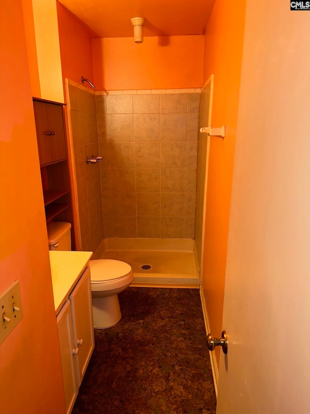 bathroom featuring vanity, toilet, and a tile shower