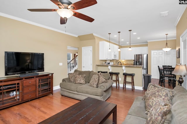 living room with light wood-type flooring, ceiling fan, and ornamental molding