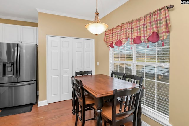 dining space with ornamental molding and light hardwood / wood-style flooring