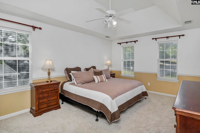 carpeted bedroom featuring a raised ceiling and ceiling fan