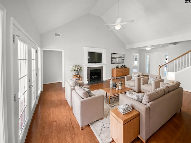 living room featuring a tile fireplace, ceiling fan, light hardwood / wood-style flooring, and plenty of natural light