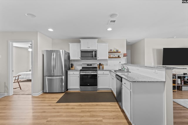 kitchen with white cabinets, stainless steel appliances, and light hardwood / wood-style flooring