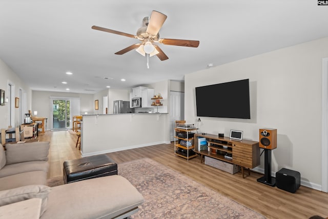 living room with light wood-type flooring and ceiling fan