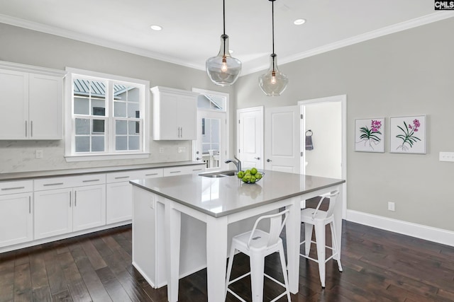 kitchen with a kitchen island with sink, sink, white cabinets, dark hardwood / wood-style floors, and hanging light fixtures