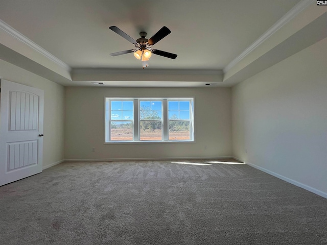 carpeted empty room with ceiling fan, crown molding, and a tray ceiling