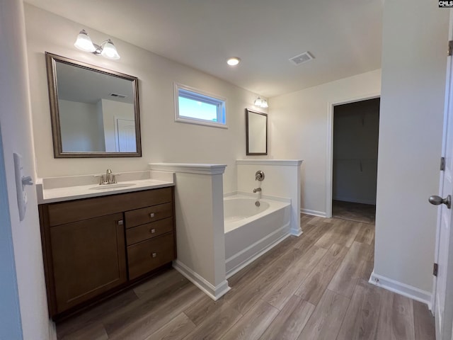 bathroom with hardwood / wood-style floors, vanity, and a bath