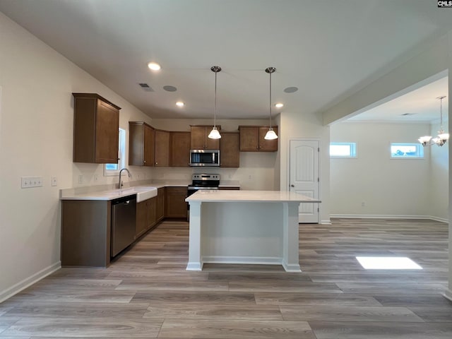 kitchen featuring stainless steel appliances, sink, a chandelier, a center island, and light hardwood / wood-style floors