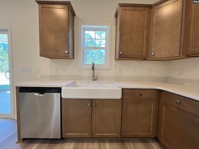 kitchen with light hardwood / wood-style flooring, stainless steel dishwasher, and sink