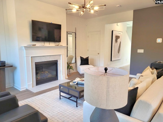 living room featuring a high end fireplace, light hardwood / wood-style floors, and an inviting chandelier