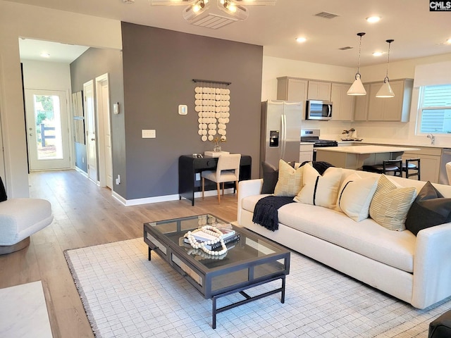 living room featuring ceiling fan, a healthy amount of sunlight, sink, and light hardwood / wood-style flooring