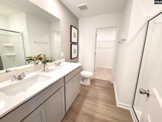 bathroom featuring wood-type flooring, vanity, toilet, and a shower with shower door