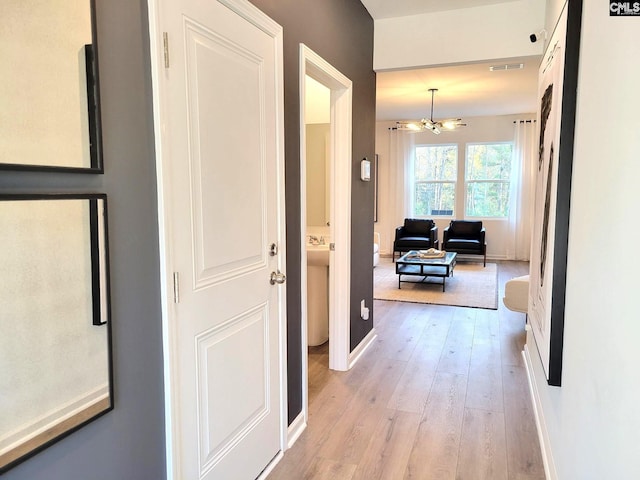 hall featuring light hardwood / wood-style flooring and a notable chandelier