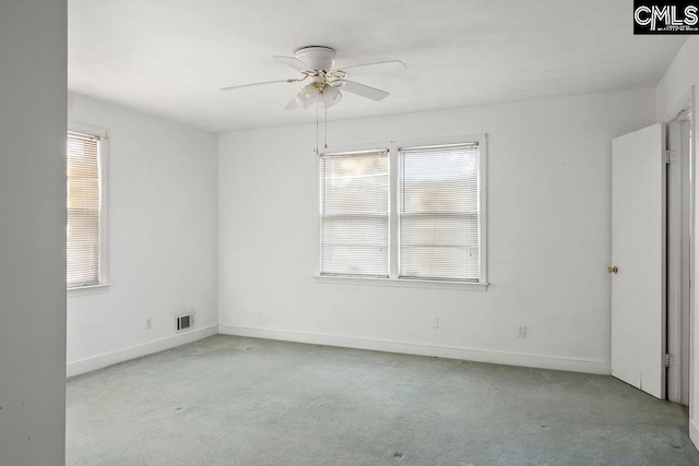 empty room featuring ceiling fan, light colored carpet, and a wealth of natural light