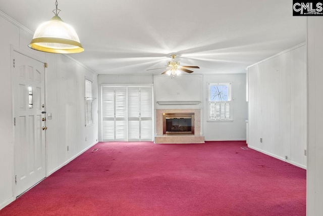 unfurnished living room with ceiling fan, ornamental molding, and carpet floors