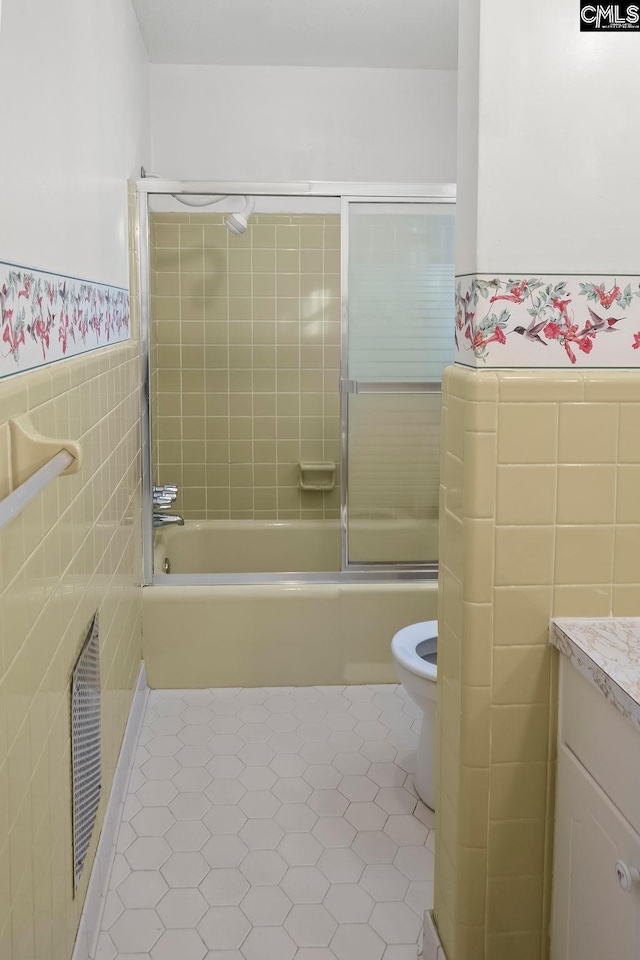 full bathroom with toilet, vanity, tile patterned flooring, tile walls, and tiled shower / bath