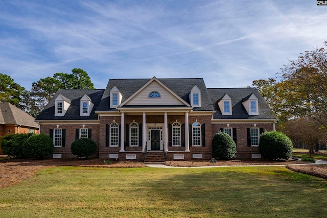 new england style home with covered porch and a front lawn