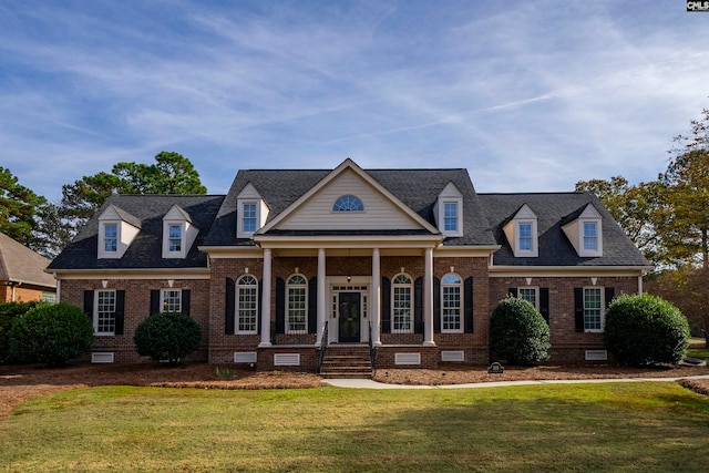 cape cod home featuring covered porch and a front yard