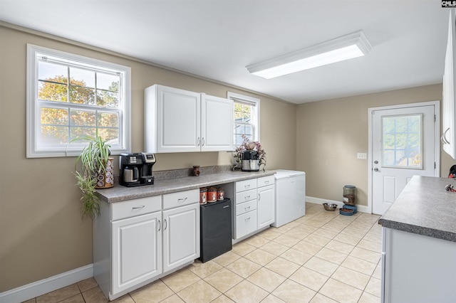 kitchen with white cabinetry, light tile patterned floors, and fridge