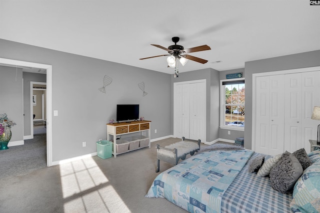 carpeted bedroom with ceiling fan and two closets