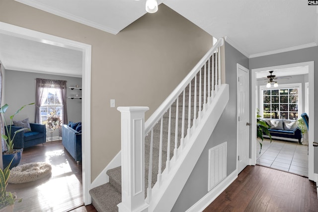 stairway featuring ceiling fan, wood-type flooring, and ornamental molding