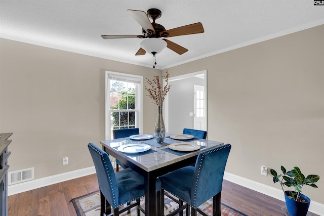 dining space featuring a textured ceiling, crown molding, ceiling fan, and dark wood-type flooring